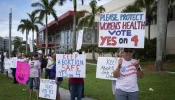 People hold up signs during a pro-abortion rally on the second anniversary of the Supreme Court ruling to overturn Roe v. Wade in West Palm Beach, Florida, on June 24, 2024.