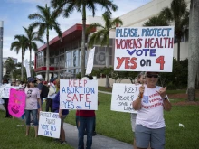 People hold up signs during a pro-abortion rally on the second anniversary of the Supreme Court ruling to overturn Roe v. Wade in West Palm Beach, Florida, on June 24, 2024.