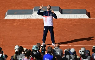 Gold medalist Novak Djokovic of Serbia poses for photographers with his medal at the presentation ceremony for the men's singles tennis event on Court Philippe-Chatrier at the Roland-Garros Stadium during the Paris 2024 Olympic Games on Aug. 4, 2024. Credit: Miguel Medina/AFP /Getty Images