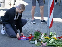 A woman kneels at a makeshift memorial of flowers and candles for the victims on Aug. 24, 2024, close to the scene where at least three people were killed and several injured when a man attacked them with a knife on Aug. 23, 2024, in Solingen, western Germany, during a festival to mark the city’s 650th anniversary.