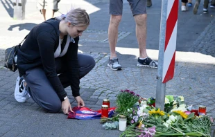 A woman kneels at a makeshift memorial of flowers and candles for the victims on Aug. 24, 2024, close to the scene where at least three people were killed and several injured when a man attacked them with a knife on Aug. 23, 2024, in Solingen, western Germany, during a festival to mark the city’s 650th anniversary. Credit: Roberto Pfeil/AFP via Getty Images