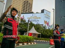 Indonesian police direct traffic next to billboards displaying a welcome message for Pope Francis in Jakarta on Sept. 2, 2024.