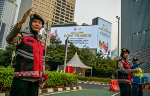 Indonesian police direct traffic next to billboards displaying a welcome message for Pope Francis in Jakarta on Sept. 2, 2024. Credit: BAY ISMOYO/AFP via Getty Images