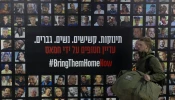 A soldier passes by a wall covered with photos of hostages held by Hamas after the deadly Oct. 7, 2023, attack in a Tel Aviv train station on Jan. 14, 2025, Tel Aviv, Israel.