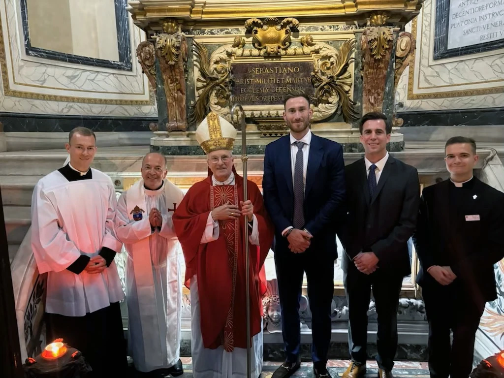 Former NBA All-Star Gordon Hayward (center) at the tomb of St. Sebastian at Rome’s Cathedral of St. Sebastian after entering the Catholic Church this year. He received the sacraments of initiation from Archbishop Timothy Broglio, USCCB president and archbishop of the Archdiocese for the Military Services, USA.?w=200&h=150