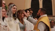 Father David Reamsnyder receives Anna West and other students into the Church at St. Anthony Parish in Hillsdale, Michigan, on Easter.