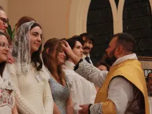 Father David Reamsnyder receives Anna West and other students into the Church at St. Anthony Parish in Hillsdale, Michigan, on Easter.