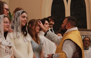 Father David Reamsnyder receives Anna West and other students into the Church at St. Anthony Parish in Hillsdale, Michigan, on Easter. Credit: Rosemary Surdyke