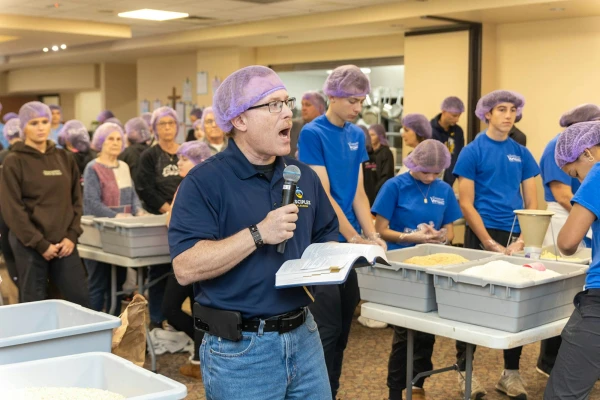 Deacon Jeffrey Loeb of St. Isidore Parish reads a passage from Scripture as volunteers pause to pray during a massive food packaging operation Nov. 2, 2024 at the Macomb, Michigan, church. Credit: Steven Stechschulte/Special to Detroit Catholic