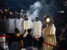 Father Boniface Hicks, O.S.B., a sought-after spiritual director and retreat master, processes the massive golden monstrance containing the Eucharist into the midst of the assembled crowd in Lucas Oil Stadium.