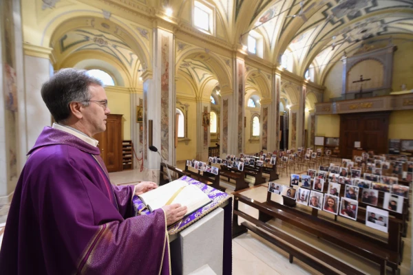 Otac Don Giuseppe slavi misu ispred portreta i selfija koje su župljani poslali 17. ožujka 2020. u Robbianu u Italiji. Kredit: Pier Marco Tacca/Getty Images