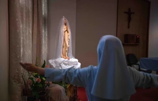 A Japanese nun holds her arms out as she prays at a chapel in her convent in Nagasaki, Japan. Credit: Carl Court/Getty Images