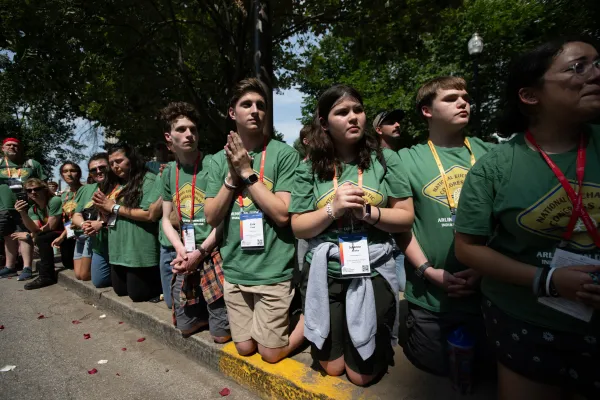 Jonge deelnemers knielen terwijl de eucharistieviering voorbijgaat in het centrum van Indianapolis. Credit: Jeffrey Bruno