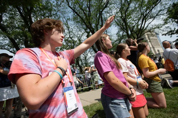 Jonge deelnemers knielen terwijl de eucharistieviering voorbijgaat in het centrum van Indianapolis. Credit: Jeffrey Bruno