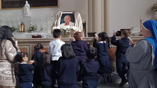 Saint John Paul the Great Academy students pray before a picture of St. John Paul II. Credit: Saint John Paul the Great Academy