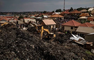 People look on as an excavator helps search for people trapped under debris after a landfill collapsed in Kampala, Uganda, on Aug. 10, 2024. Eight people including two children were killed when mountains of garbage collapsed at a landfill, the city authority said. Credit: Badru Katumba/AFP via Getty Images