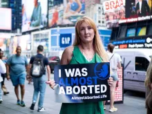 Rebecca Kiessling holds a sign at the Almost Aborted launch event on June 7, 2024, in Times Square in New York City. Kiessling was conceived in rape, and her mother almost chose abortion, but life-affirming legislation protected her.