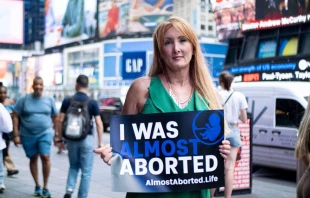 Rebecca Kiessling holds a sign at the Almost Aborted launch event on June 7, 2024, in Times Square in New York City. Kiessling was conceived in rape, and her mother almost chose abortion, but life-affirming legislation protected her. Credit: Photo courtesy of Students for Life of America