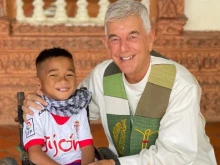 Father “Kike” Figaredo with one of the disabled children he helps in Cambodia.