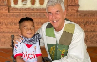 Father “Kike” Figaredo with one of the disabled children he helps in Cambodia. Credit: Courtesy of Father Kike Figuredo