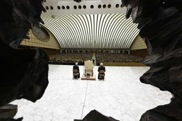 A view of Pope Francis addressing the faithful from the stage of the Vatican's Paul VI Audience Hall during the first Jubilee audience of 2025, seen through the distinctive carved stone entranceway. Credit: Vatican Media