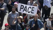 Pilgrims in St. Peter’s Square hold up a sign that says “pace,” which means “peace” in Italian.