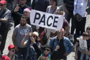 Pilgrims in St. Peter's Square hold up a sign that says "pace," which means "peace" in Italian.