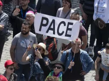 Pilgrims in St. Peter’s Square hold up a sign that says “pace,” which means “peace” in Italian.