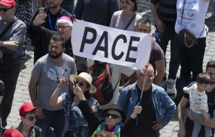 Pilgrims in St. Peter’s Square hold up a sign that says “pace,” which means “peace” in Italian. Credit: Vatican Media