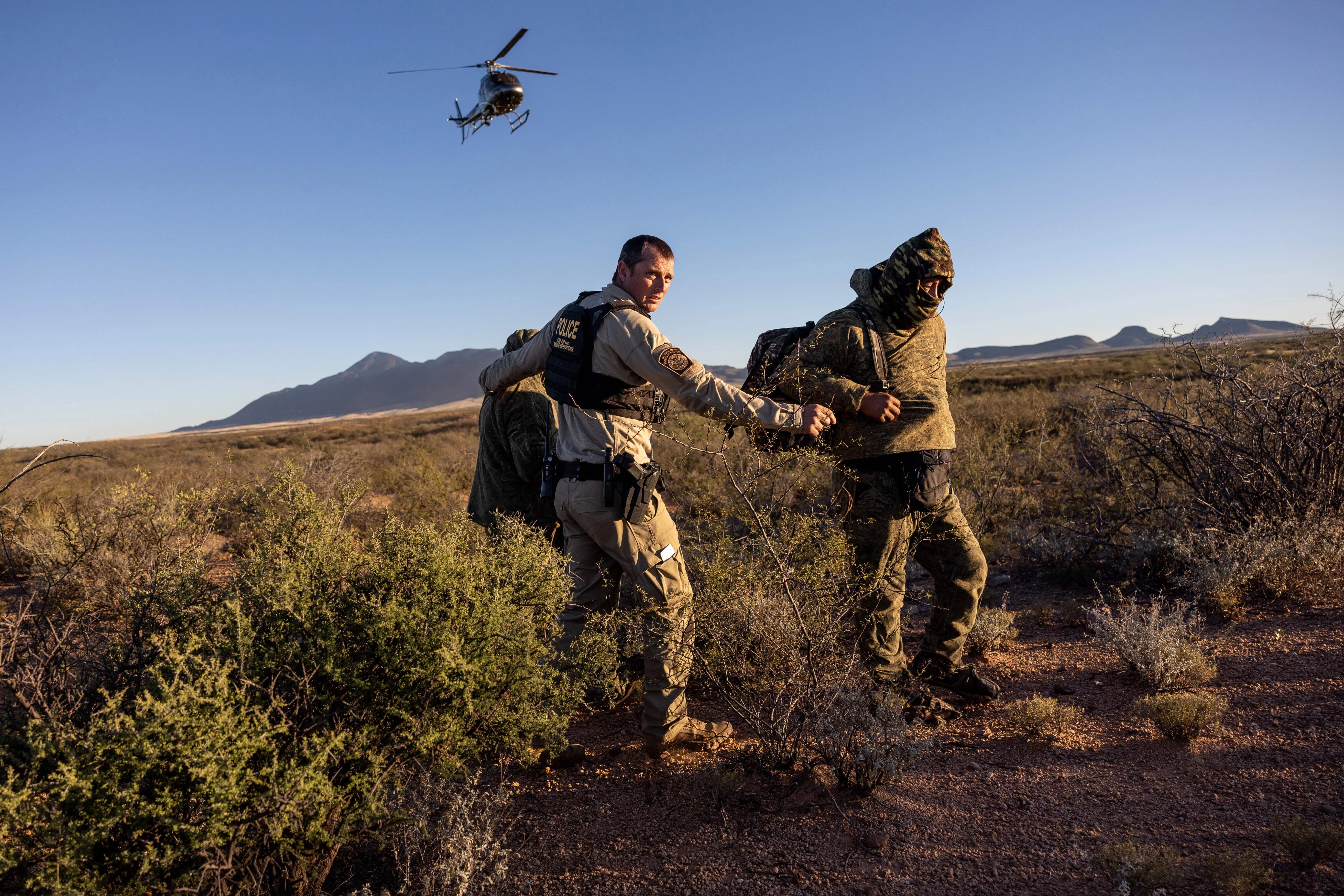 A U.S. Customs and Border Protection agent detains camouflaged Mexican migrants near the U.S.-Mexico border on Nov. 4, 2022, near Naco, Arizona.?w=200&h=150