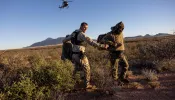 A U.S. Customs and Border Protection agent detains camouflaged Mexican migrants near the U.S.-Mexico border on Nov. 4, 2022, near Naco, Arizona.