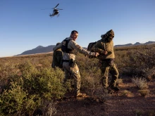 A U.S. Customs and Border Protection agent detains camouflaged Mexican migrants near the U.S.-Mexico border on Nov. 4, 2022, near Naco, Arizona.