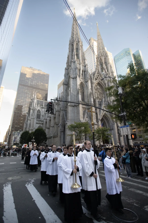 Seminarians holding a cross and candles lead a Eucharistic procession out of St. Patrick’s Cathedral in New York City on Oct. 15, 2024. Credit: Jeffrey Bruno