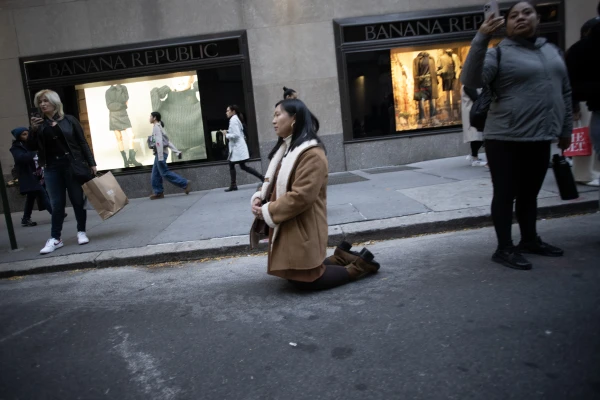 A woman kneels as the Eucharistic procession sponsored by the Napa Institute passes by on the streets of New York City on Oct. 15, 2024. Credit: Jeffrey Bruno