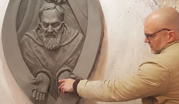 Artist Timothy P. Schmalz touches the hands of Padre Pio in one of his sculptures. Credict: Photo courtesy of Timothy P. Schmalz