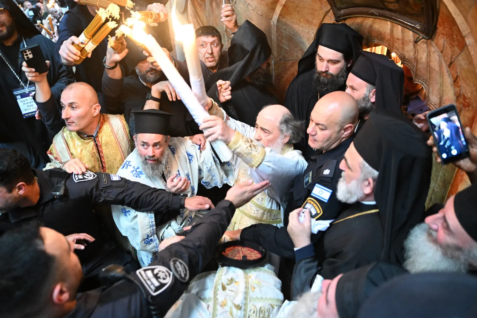 The Greek Orthodox Patriarch Theophilos III exits the Aedicule of the Holy Sepulcher on May 4, 2024, in Jerusalem, showing the faithful the two candles just lit from the oil lamp that is believed to have been miraculously ignited inside Jesus' tomb.?w=200&h=150