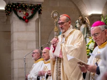 Cardinal Pierbattista Pizzaballa, Latin patriarch of Jerusalem, leans on his pastoral staff while listening to the proclamation of the Gospel during the Christmas Eve Mass at the Church of St. Catherine, the Latin section of the Basilica of the Nativity, on Dec. 24, 2024.