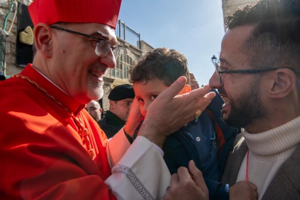 Cardinal Pierbattista Pizzaballa, the Latin Patriarch of Jerusalem, stops to greet some worshipers and bless a child during his arrival in Bethlehem for the Christmas holidays on December 24, 2024. Credit: Marinella Bandini