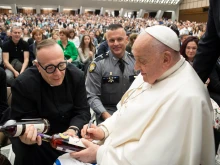 Pope Francis signs two bottles of bourbon presented to him by Father Jim Sichko at the Vatican on May 1, 2024.