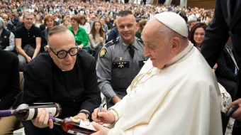 Pope Francis signs two bottles of bourbon presented to him by Father Jim Sichko at the Vatican on May 1, 2024.