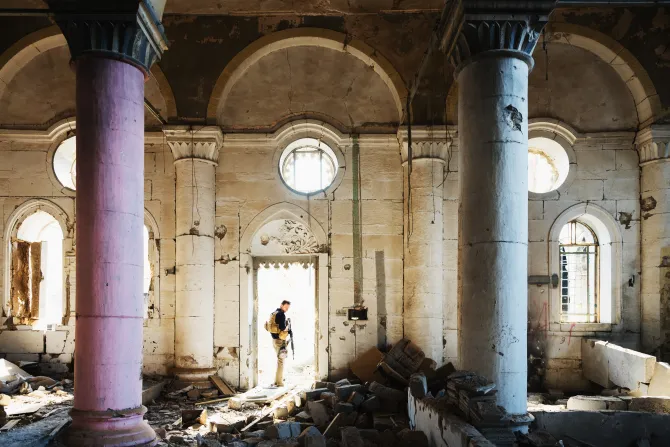 An unknown security guard stands at the entrance of a church destroyed during the fighting with ISIS in Mosul, Iraq.?w=200&h=150