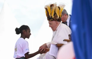 Pope Francis wears a traditional head dress as greets a young girl in Vanimo, Papua New Guinea, Sept. 8, 2024. Credit: Vatican Media