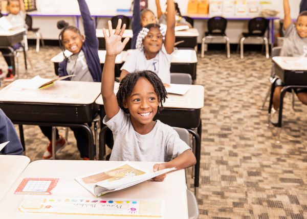 An elementary student raises his hand in class at St. Francis School in Cleveland in 2022. Credit: Leila Sutton/Partnership Schools
