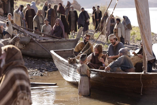 The disciple Peter speaking with a young boy as he sits in a fishing boat in the new film 