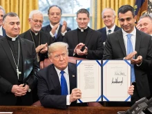 President Donald J. Trump is joined by legislators and Archbishop Bashar Warda of Erbil-Kurdistan, Iraq, left, as he signs H.R. 390, the Iraq and Syria Genocide Relief and Accountability Act of 2018 on Dec. 11, 2018, in the Oval Office of the White House.