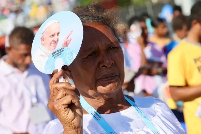 A woman holds a fan featuring Pope Francis during Mass with the Roman pontiff at Sir John Guise Stadium in Port Moresby, Papua New Guinea